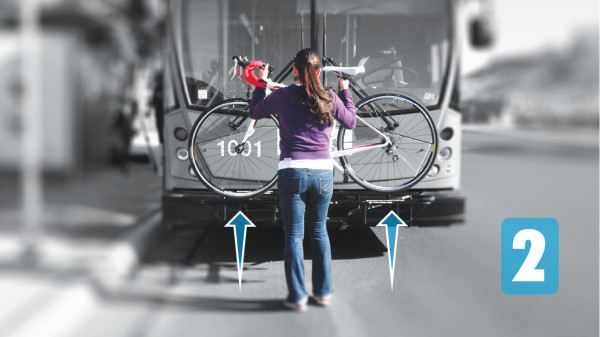 Cyclist inserting bicycle onto external bike rack.